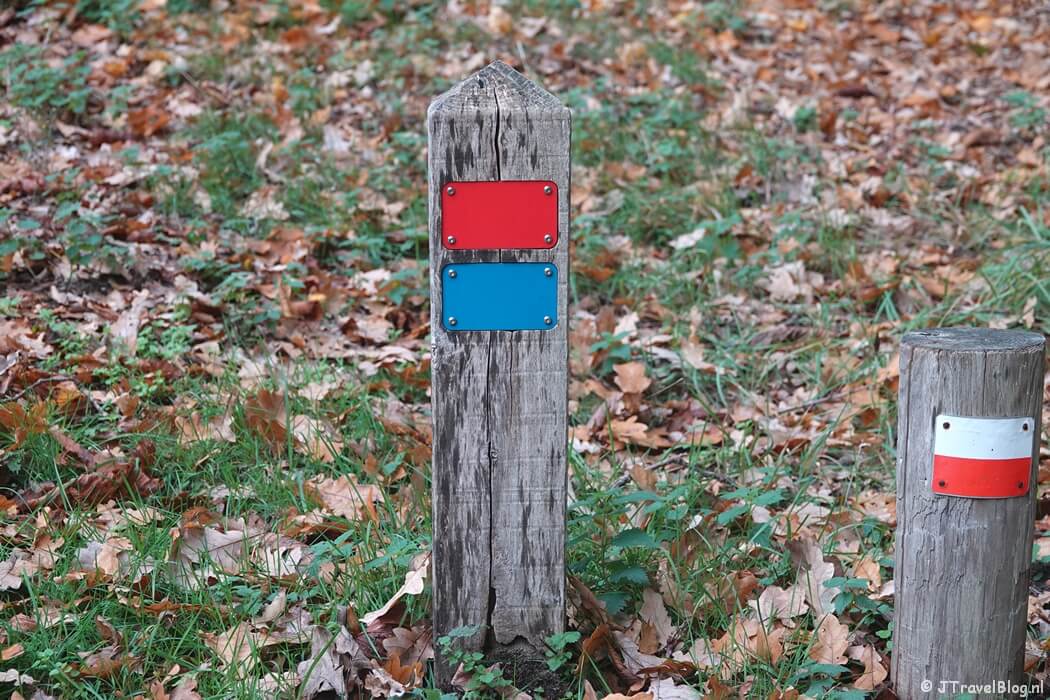 Een rood en blauw routepaaltje tijdens de rode wandelroute vanaf ingang Panneland in de Amsterdamse Waterleidingduinen