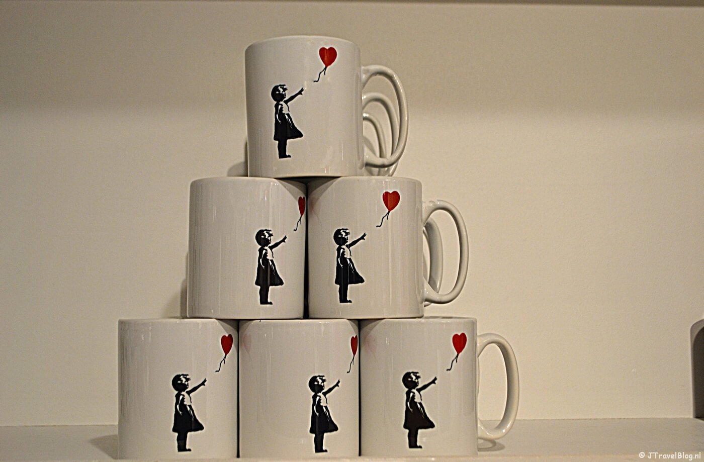 Mokken met de afbeelding Girl with Balloon van Banksy in de museumwinkel.